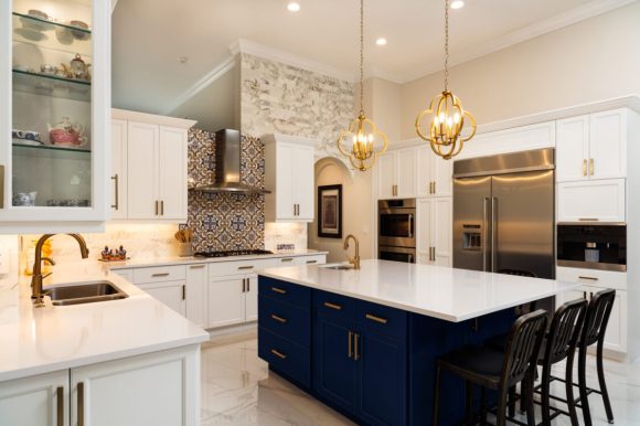 Luxury kitchen featuring navy island, gold pendant lights, and marble flooring. A residential remodel example by L&M Construction.