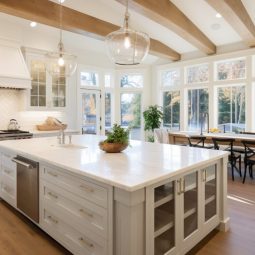 Spacious kitchen featuring striped bar stools, wrought iron pendant lights, and architectural ceiling details.
